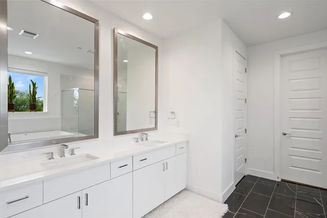 a spacious bathroom with a double vanity sink a mirror and a shower