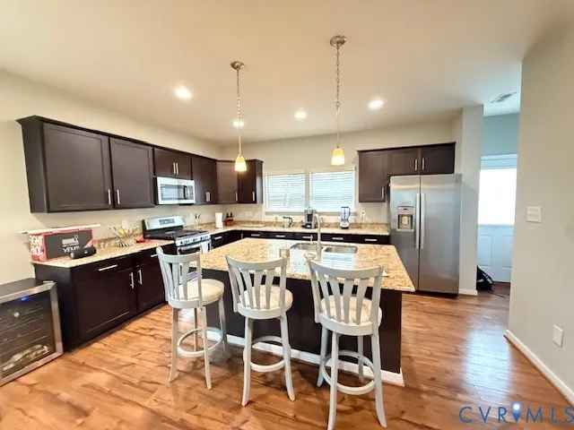 a kitchen with stainless steel appliances granite countertop a stove top oven a refrigerator a sink and a chairs