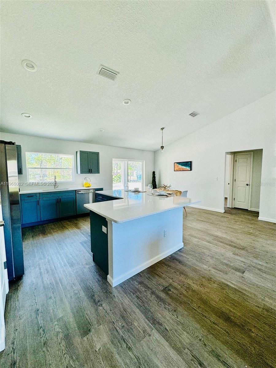 13731 Southwest 89 Circle Ocala, FL 34473 - Photo 8 of 24 a large kitchen with kitchen island wooden floors and stainless steel appliances