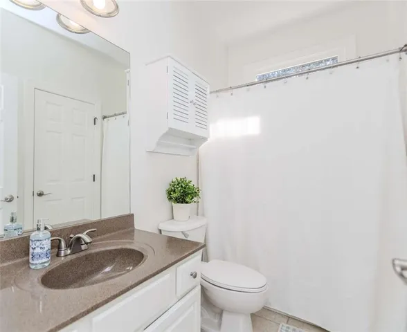 a bathroom with a granite countertop sink a toilet and shower