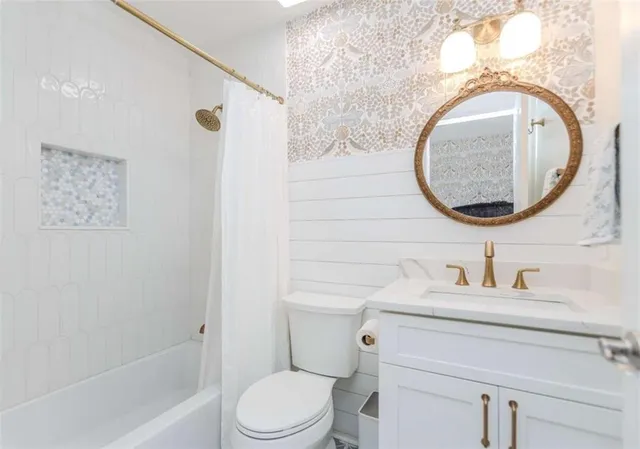 a bathroom with a toilet sink vanity mirror and shower