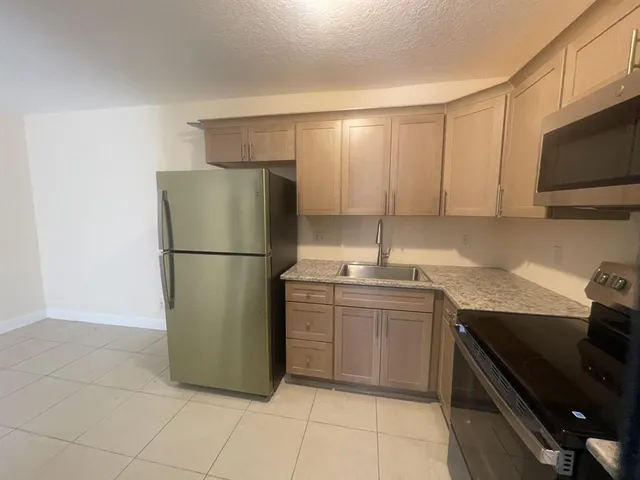 a kitchen with stainless steel appliances granite countertop a refrigerator and a sink