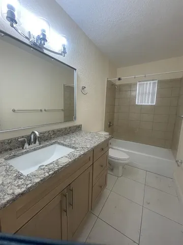 a bathroom with a granite countertop sink a toilet and bathtub