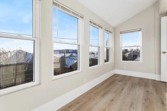 a view of an empty room with a window and wooden floor