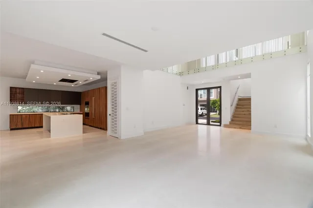 a view of an empty room with kitchen and a window