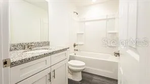a bathroom with a granite countertop sink a toilet and bathtub