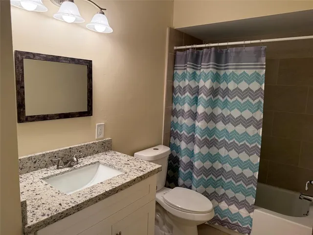a bathroom with a granite countertop sink a mirror and a toilet
