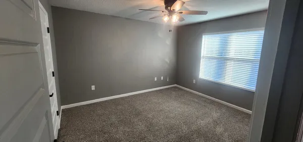 an empty room with a window and a fan
