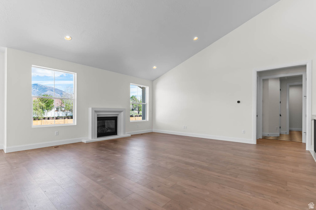 11749 South Halls Crk Road Draper, UT 84020 - Photo 12 of 21 Unfurnished living room featuring a glass covered fireplace, lofted ceiling, dark wood finished floors, recessed lighting, and a mountain view