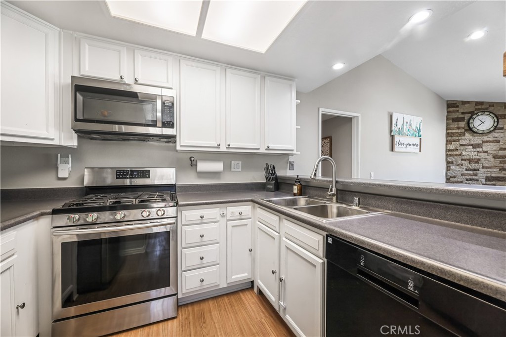3512 West Stonepine Lane, Unit D Anaheim, CA 92804 - Photo 11 of 38 a kitchen with stainless steel appliances granite countertop a sink a stove a microwave and wooden cabinets