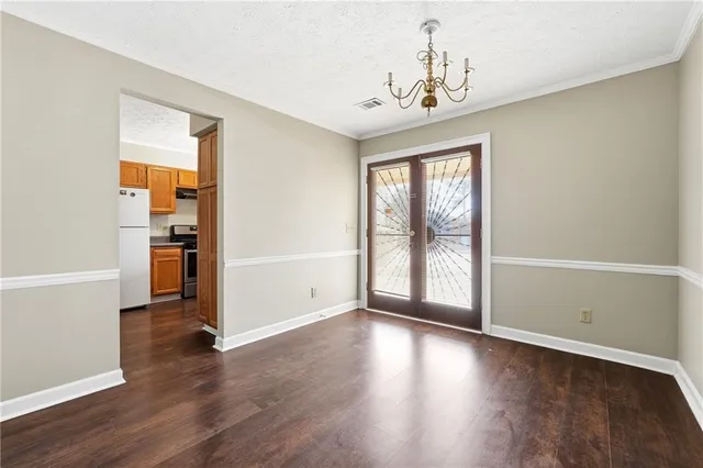 an empty room with wooden floor chandelier and windows