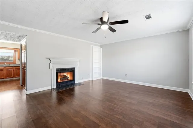 an empty room with wooden floor fireplace and windows