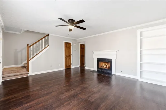a view of an empty room with wooden floor fireplace and a window