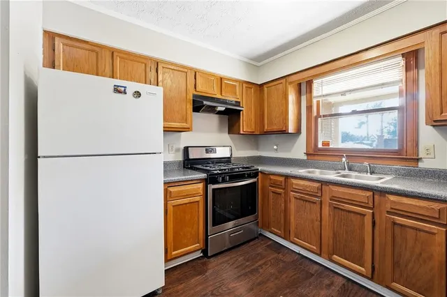 a kitchen with stainless steel appliances granite countertop a refrigerator a sink dishwasher a stove and a refrigerator