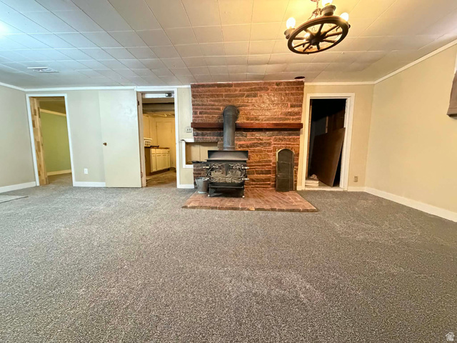156 D Street Helper, UT 84526 - Photo 19 of 24 Unfurnished living room featuring a wood stove, carpet floors, and ornamental molding