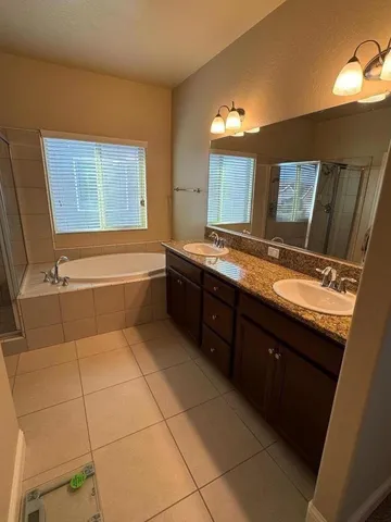 a bathroom with a granite countertop sink a large mirror and a bathtub