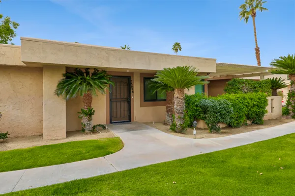 a front view of a house with a yard and potted plants