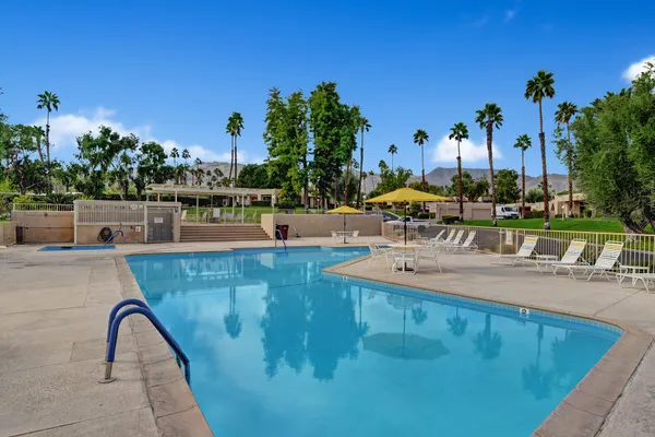 a view of a swimming pool with a bench and trees in the background
