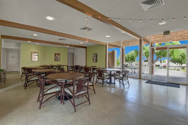 a dining hall with stainless steel appliances a dining table and chairs with a large window