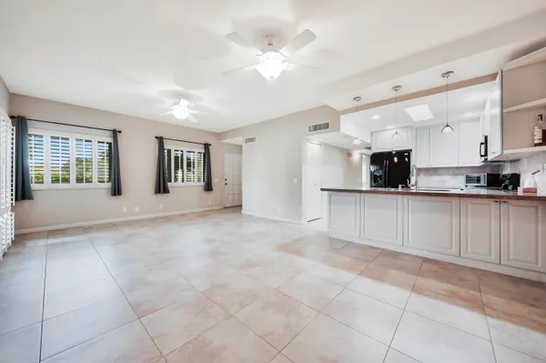 a view of an empty room with kitchen and window