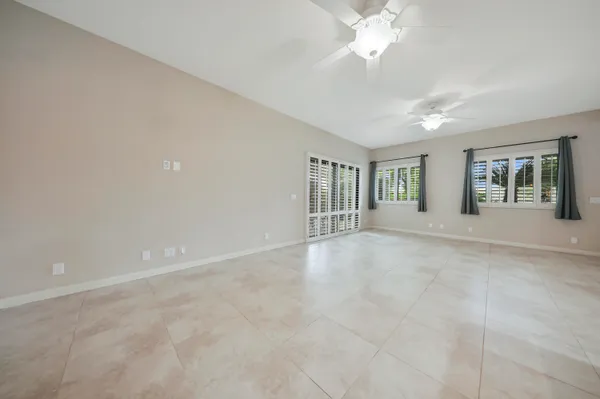 a view of an empty room with chandelier fan and window