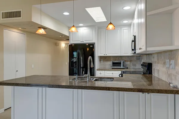 a kitchen with stainless steel appliances granite countertop a sink and a white cabinets