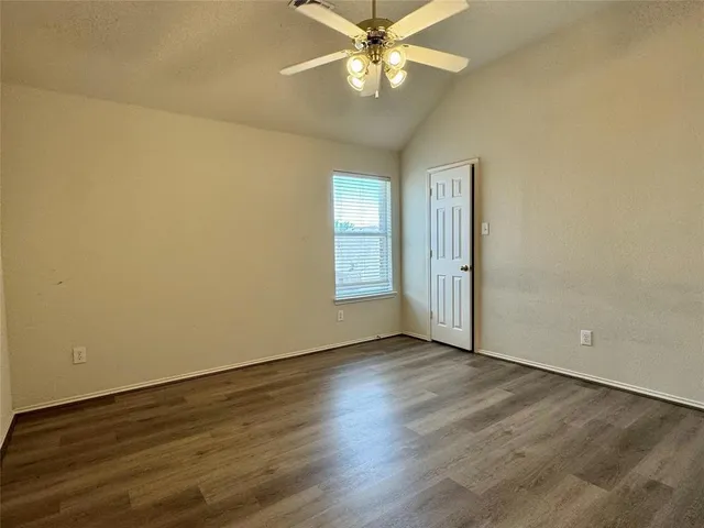 an empty room with wooden floor fan and windows