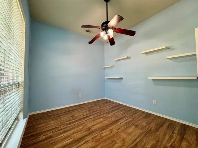 a view of a room with a hanging light and hardwood floor