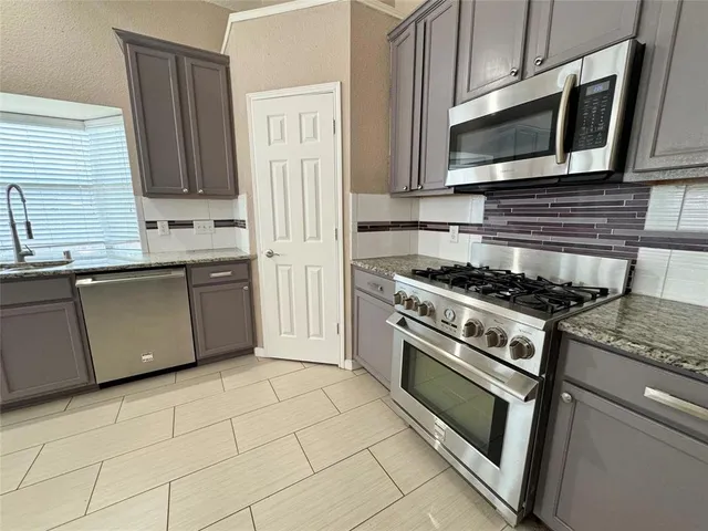a kitchen with granite countertop a stove top oven microwave and cabinets