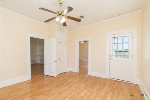 an empty room with wooden floor and ceiling fan