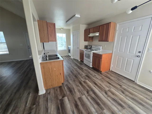 a kitchen with sink a refrigerator a stove top oven a washer dryer and white cabinets