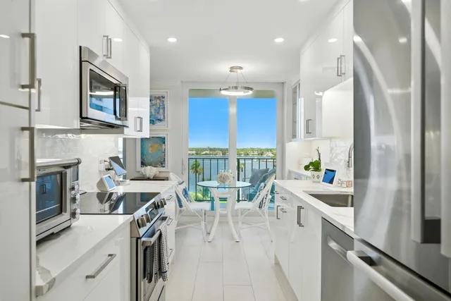 a kitchen with stainless steel appliances granite countertop a refrigerator a sink dishwasher a stove and a dining table with wooden floor