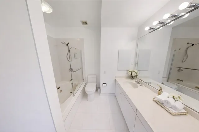 a spacious bathroom with a double vanity sink a large mirror and shower