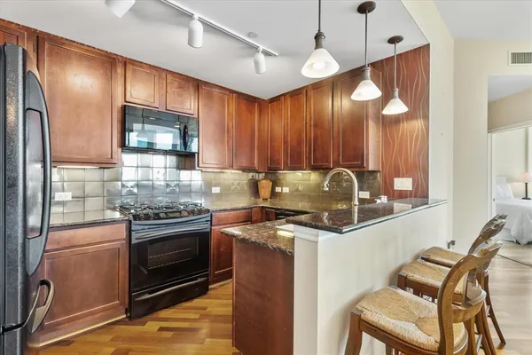 a kitchen with granite countertop stainless steel appliances wooden cabinets and a stove top oven