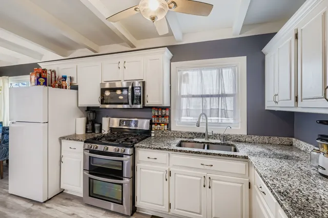 a kitchen with granite countertop a sink appliances and cabinets