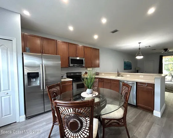 a kitchen with a dining table chairs refrigerator and microwave