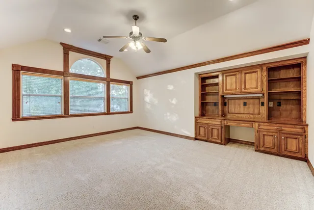 an empty room with chandelier fan and windows