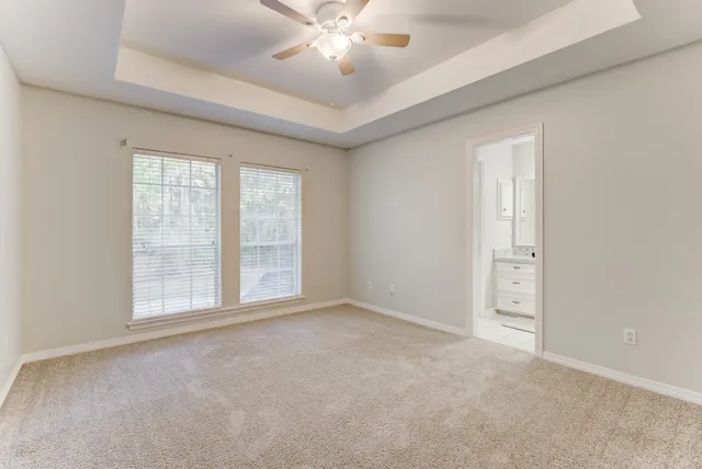 an empty room with chandelier fan and windows