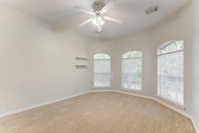 an empty room with windows and fan