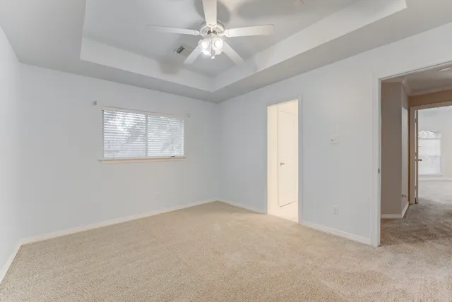 an empty room with windows and fan