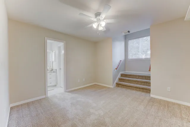 an empty room with a ceiling fan and window