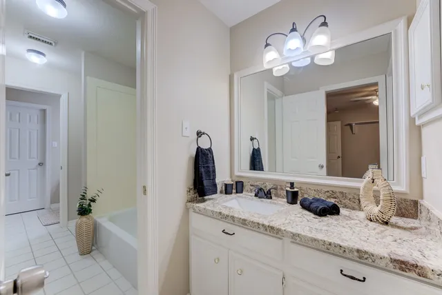 a bathroom with a granite countertop sink a light fixture and a mirror