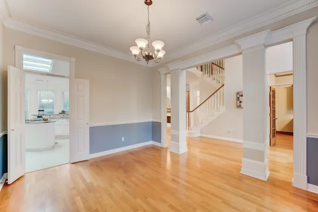 a view of an empty room with wooden floor and a kitchen