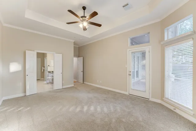 an empty room with chandelier fan and windows