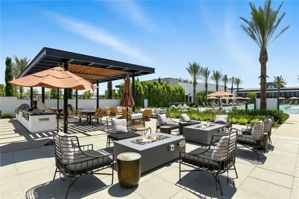 a view of patio with chairs and table under an umbrella with potted plants