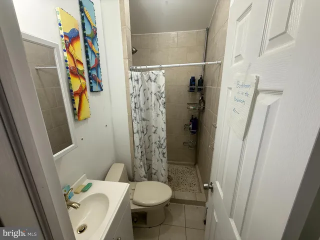 a white toilet sitting next to a bathroom sink and a shower curtain