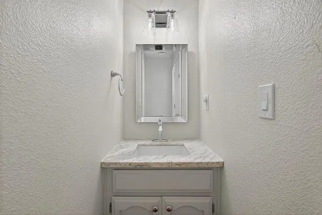 a bathroom with a granite countertop sink and a mirror