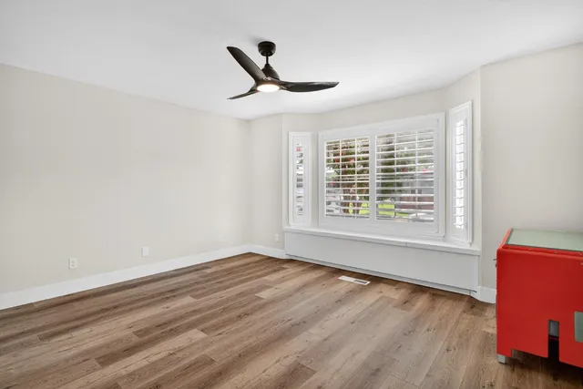 a view of an empty room with a window and wooden floor