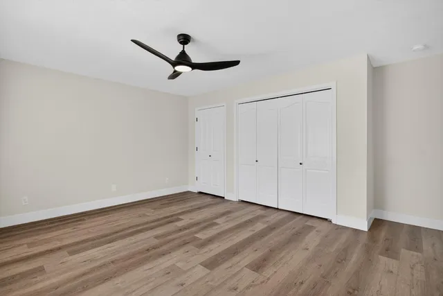 a view of a room with wooden floor closet ceiling fan and window