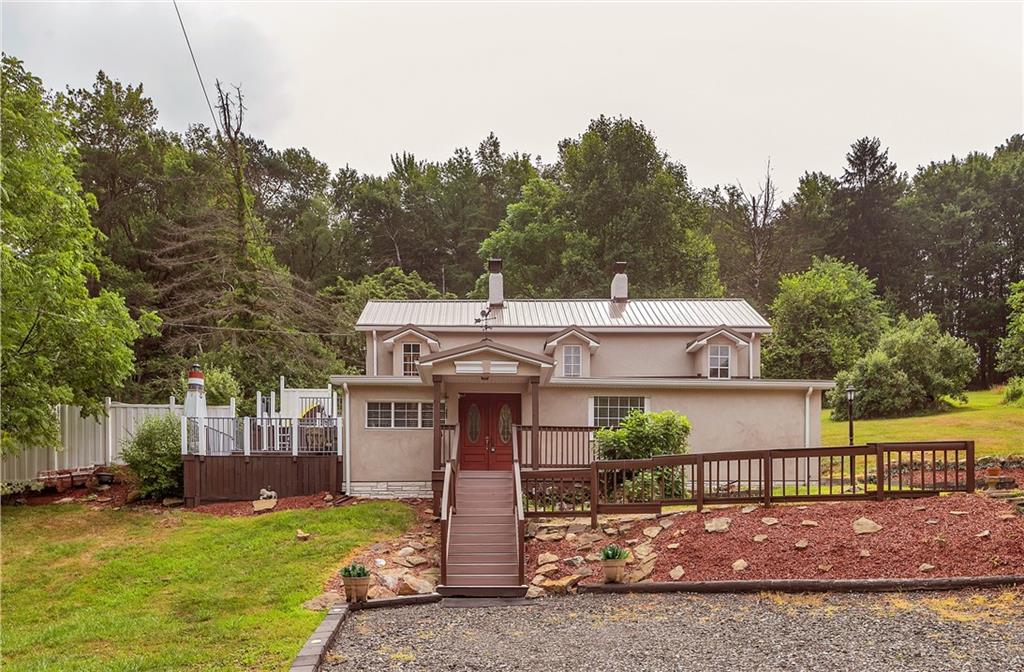 a view of a house with a yard balcony and tree in the background